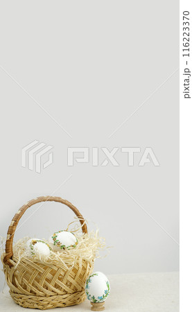 Handmade art. Thread embroidery on eggs. Easter in a wicker straw basket there are white eggs with a beautiful decoration of ribbons to embroider at home Handmade art. Thread embroidery on eggs. Easter in a wicker straw basket there are white eggs with a beautiful decoration of ribbons to embroider at home 116223370