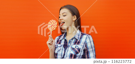Portrait happy cheerful smiling teenager girl holding colorful lollipop on red background Portrait happy cheerful smiling teenager girl holding colorful lollipop on red background 116223772
