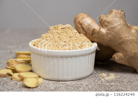 Ground ginger root powder natural spice seasoning on gray stone background 116224249