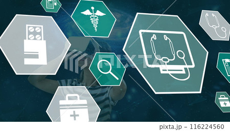 Image of medical icons falling over woman using vr headset 116224560