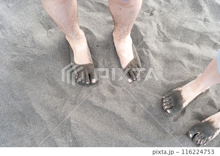 Bare foot on black sand, black volcanic beach barefoot person, dirty family feet on dark sea sand 116224753