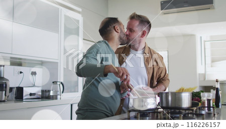 Image of light spots over diverse male couple cooking dinner in kitchen 116226157