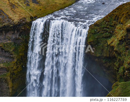 Impressively beautiful nature of Iceland during sunset. Skogafoss waterfall is one famous natural landmark and travel destination place of Iceland. Tourists ride horses near famouse waterfall. Impressively beautiful nature of Iceland during sunset. Skogafoss waterfall is one famous natural landmark and travel destination place of Iceland. Tourists ride horses near famouse waterfall. 116227789