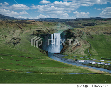 Impressively beautiful nature of Iceland during sunset. Skogafoss waterfall is one famous natural landmark and travel destination place of Iceland. Tourists ride horses near famouse waterfall. 116227877