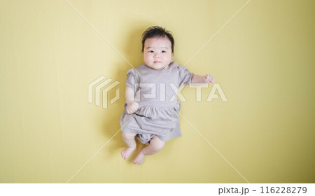 黄色バックに寝転ぶ女の子の赤ちゃん 黄色バックに寝転ぶ女の子の赤ちゃん 116228279
