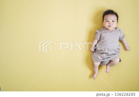 黄色バックに寝転ぶ女の子の赤ちゃん 116228285