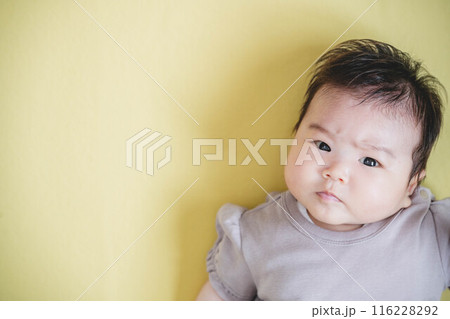 黄色バックに寝転ぶ女の子の赤ちゃん 116228292