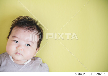黄色バックに寝転ぶ女の子の赤ちゃん 116228293