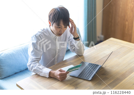通帳を見る男性 116228440
