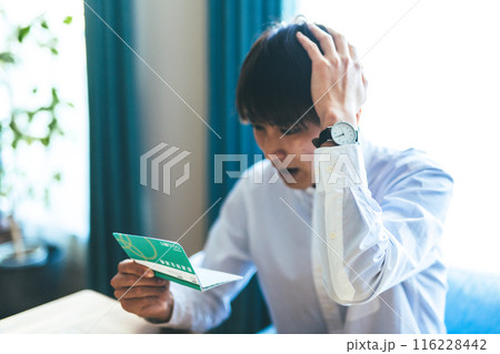 通帳を見る男性 116228442