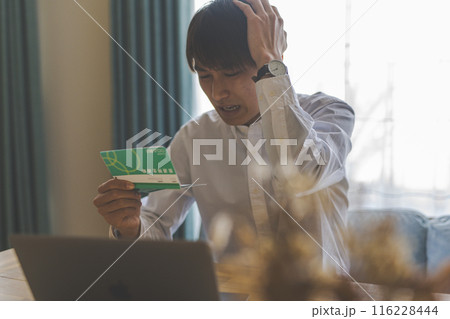 通帳を見る男性 116228444