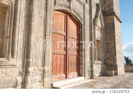 Old wooden door on a weathered stone Church of Timios Prodromos facade at Vouni village. Limassol District, Cyprus Old wooden door on a weathered stone Church of Timios Prodromos facade at Vouni village. Limassol District, Cyprus 116228752