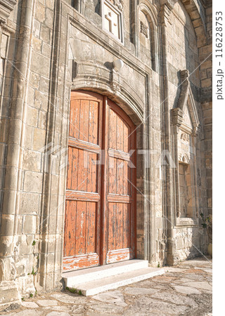 Old wooden door on a weathered stone Church of Timios Prodromos facade at Vouni village. Limassol District, Cyprus Old wooden door on a weathered stone Church of Timios Prodromos facade at Vouni village. Limassol District, Cyprus 116228753