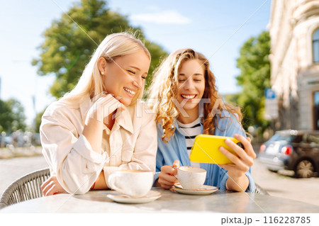 Two young women sitting in the cafe. Coffee break after shopping. Blogging, tourism. 116228785