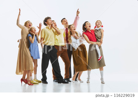 A group of people in vintage attire pointing and looking upwards with shock and excitement, isolated on white background. A group of people in vintage attire pointing and looking upwards with shock and excitement, isolated on white background. 116229019