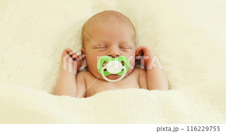Portrait of sweet baby with pacifier, infant sleeping lying on white bed at home 116229755