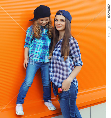Stylish mother and child daughter together, happy mom with kid girl in casual clothing in the city 116229862