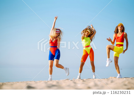 Smiling dancers in colorful swimsuits are dancing on beach ?oncept of sports, aerobics. Active sport Smiling dancers in colorful swimsuits are dancing on beach ?oncept of sports, aerobics. Active sport 116230231
