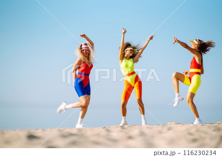 Smiling dancers in colorful swimsuits are dancing on beach ?oncept of sports, aerobics. Active sport Smiling dancers in colorful swimsuits are dancing on beach ?oncept of sports, aerobics. Active sport 116230234