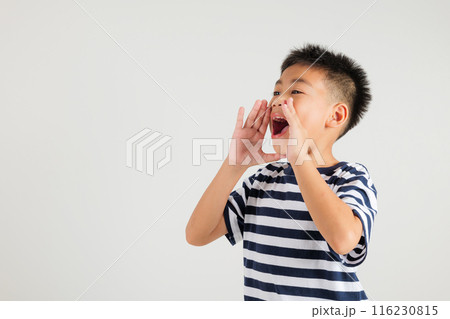 Asian happy portrait cute young kid boy standing hand on mouth talking news announcement studio shot isolated on white background, Thai primary child announcement 116230815