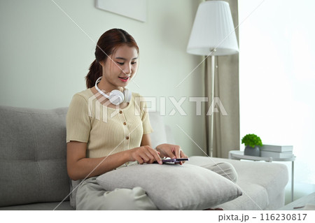 Close up view young woman sitting in lotus pose with her eyes closed on sofa at home Close up view young woman sitting in lotus pose with her eyes closed on sofa at home 116230817