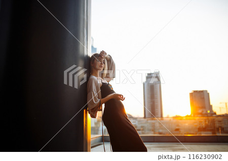 Beautiful woman standing on roof, feel happy at sunset. Freedom. Lifestyle, relaxation concept. Beautiful woman standing on roof, feel happy at sunset. Freedom. Lifestyle, relaxation concept. 116230902