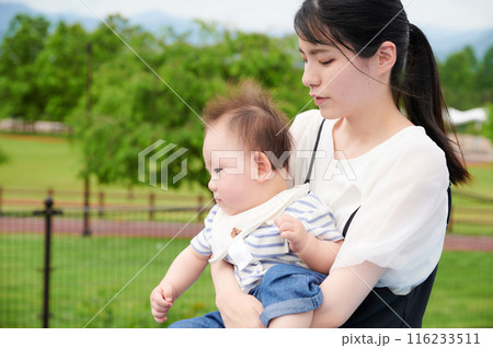 公園で赤ちゃんを抱くお母さん 公園で赤ちゃんを抱くお母さん 116233511