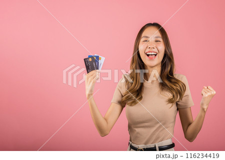 Portrait of Happy excited amazed Asian young woman holding bank card solution in hands in studio shot isolated on pink background, female smiling showing presenting credit card for online payment Portrait of Happy excited amazed Asian young woman holding bank card solution in hands in studio shot isolated on pink background, female smiling showing presenting credit card for online payment 116234419