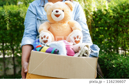 Volunteer collect cloth and doll in cardboard box to donate. Volunteer collect cloth and doll in cardboard box to donate. 116236607