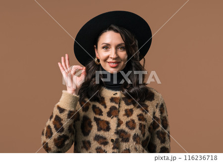 Mature woman with OKAY sign, ok gesture. Happy lady, correct choice on beige Mature woman with OKAY sign, ok gesture. Happy lady, correct choice on beige 116236718