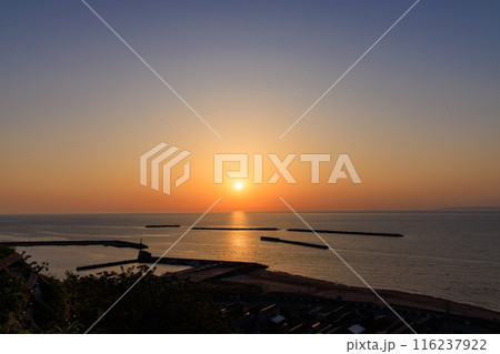 新潟の海に沈む春の夕日と空の青とオレンジの美しいグラデーション 116237922