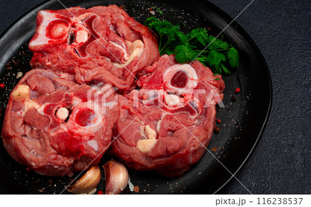 raw steak, calf's neck on the bone, fresh meat, on a black plate, top view, no people, 116238537