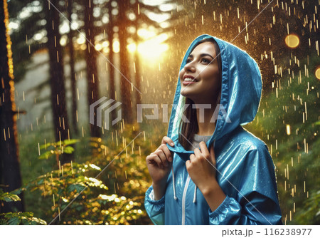 Young Woman in Blue Raincoat Enjoying Rain in Forest 116238977