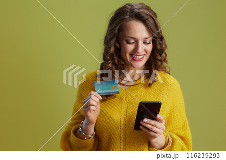 smiling fit woman in yellow sweater isolated on green 116239293