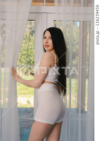 Woman In White Shorts Posing By Window In A Room 116239450