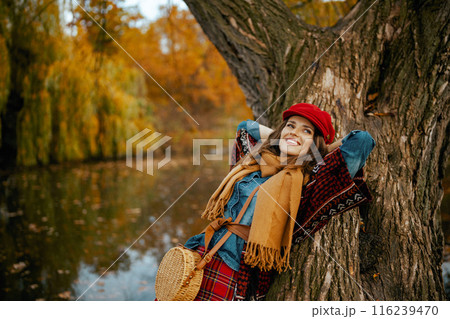 relaxed stylish woman in jeans shirt and red hat with scarf 116239470