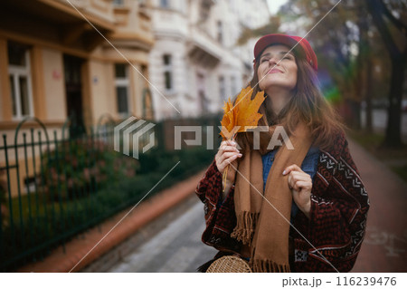 relaxed elegant woman in red hat with autumn leafs and scarf relaxed elegant woman in red hat with autumn leafs and scarf 116239476