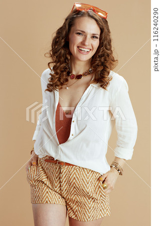 smiling woman in blouse and shorts against beige smiling woman in blouse and shorts against beige 116240290
