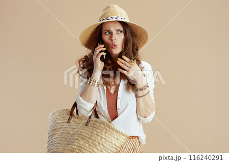 sad trendy woman in blouse and shorts talking on phone on beige sad trendy woman in blouse and shorts talking on phone on beige 116240291