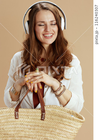 smiling trendy woman in blouse and shorts on beige 116240307