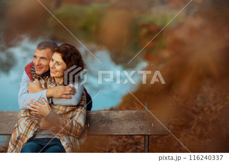 smiling stylish family in park embracing while sitting on bench smiling stylish family in park embracing while sitting on bench 116240337
