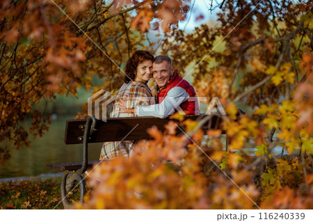 smiling modern family in park sitting on bench 116240339