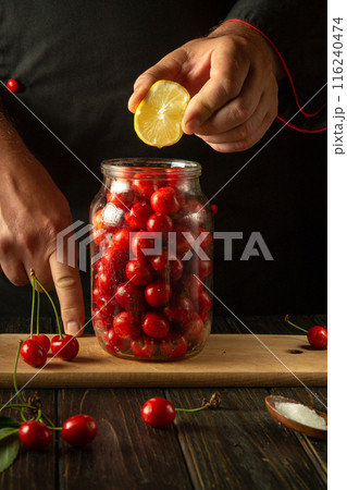 A chef adds lemon to a jar of cherries before canning. The concept of making a delicious compote from sweet cherries. Advertising space A chef adds lemon to a jar of cherries before canning. The concept of making a delicious compote from sweet cherries. Advertising space 116240474