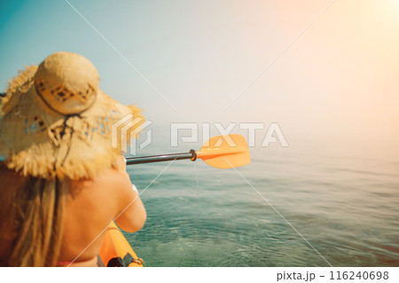 Woman in kayak back view. Happy woman with long hair in a swimsuit and hat floating in kayak on the sea. Summer holiday vacation. Summer holidays vacation at sea. 116240698
