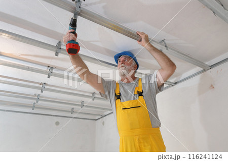 Senior adult worker fixing aluminum batten for gypsum ceiling 116241124
