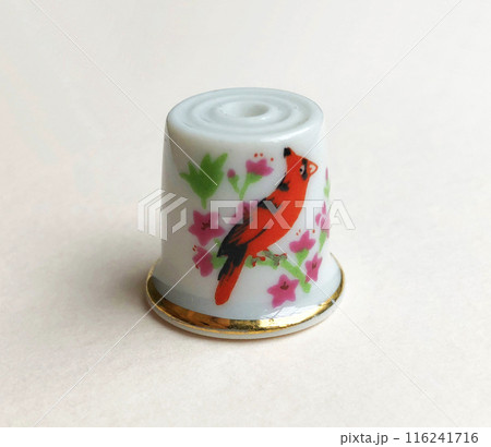 A vintage porcelain thimble is a small, delicate sewing tool made of fine porcelain, often adorned with intricate designs or hand-painted patterns 116241716