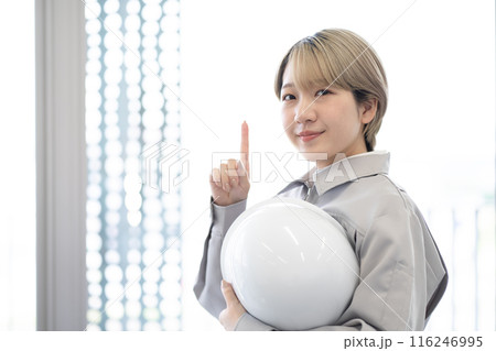 作業服を着てヘルメットを持つ金髪ショートヘアの若い女性（指さし、髪色自由、自分らしく働く、職場環境） 116246995