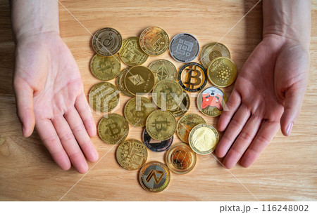 Person hands with various kinds of cryptocurrency token coins on wooden table. Person hands with various kinds of cryptocurrency token coins on wooden table. 116248002