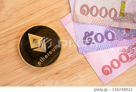 A Ethereum token with Thai Baht banknotes on wooden table. Conceptual shot of business and financial items for trading. 116248022