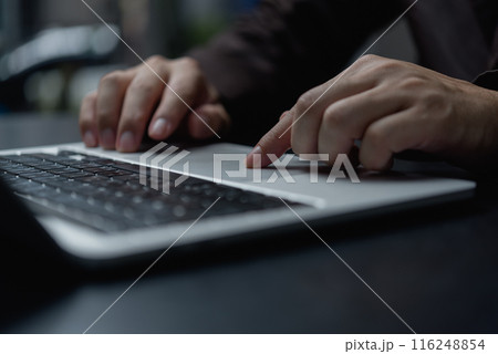 A person is typing on a laptop with a finger pointing to the screen 116248854